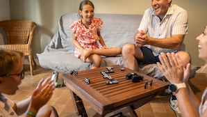 Une famille est assise sur un canapé gris, devant lequel se trouve une table basse en bois.