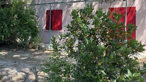 Um edifício com persianas vermelhas e um jardim à frente.