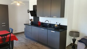 Una cocina moderna con armarios grises, una encimera negra y una mesa roja.