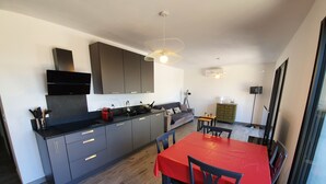 Una cocina moderna con armarios grises, una encimera negra y una mesa de comedor roja con sillas.