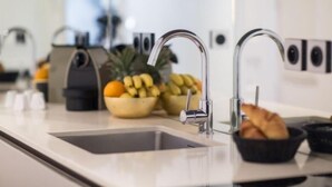 A modern kitchen with stainless steel appliances, a sink, and a bowl of fruit.