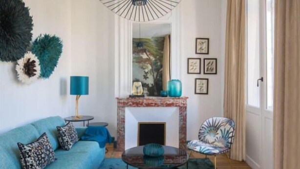 A modern living room with a blue sofa, a round coffee table, a fireplace, and a chair with a floral pattern.