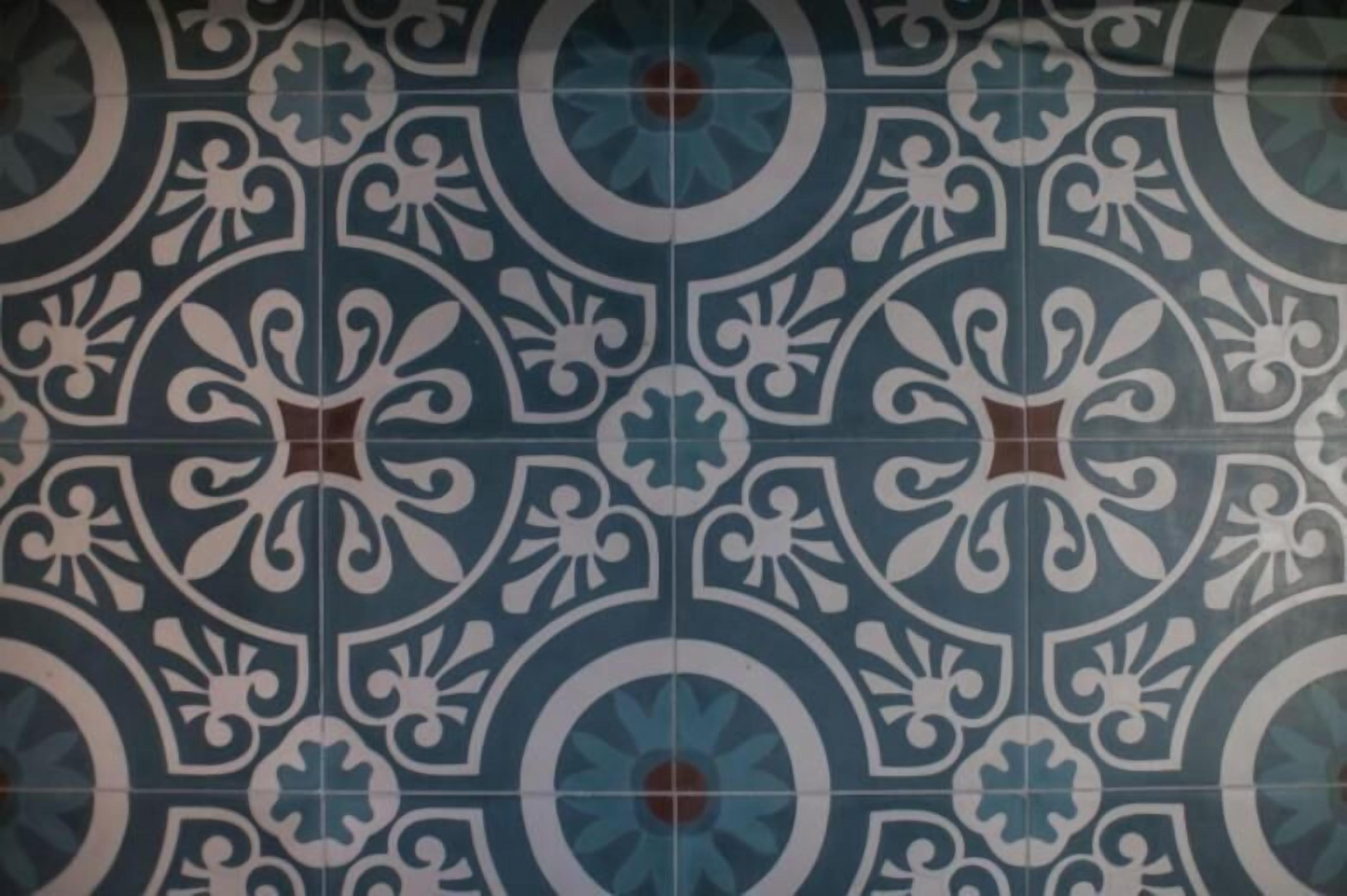 A patterned tile design with a central circular motif and symmetrical floral elements.