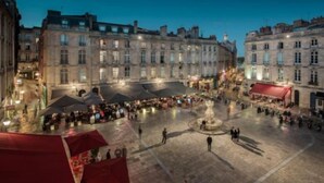 A square with historic buildings, a fountain, and outdoor seating areas.
