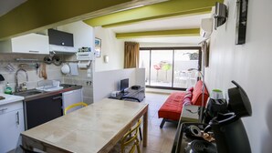 A compact kitchen with a dining area, a small sofa, and a sliding glass door leading to an outdoor area. - DUPLEX WITH GARAGE BETWEEN BEACHES AND TOWN CENTER (La Ciotat)