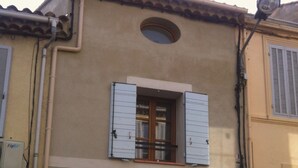 A building with a beige facade, a small window with shutters, and a large garage door. - DUPLEX WITH GARAGE BETWEEN BEACHES AND TOWN CENTER (La Ciotat)