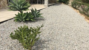 A stone building with a patio area, outdoor seating, and a gravel driveway. - Superb architect villa (TERTENIA DI MARINA)