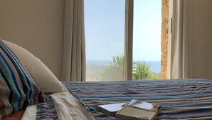 A hotel room with a bed featuring a striped bedspread, a pillow, and a box on the bed. - Superb architect villa (TERTENIA DI MARINA)