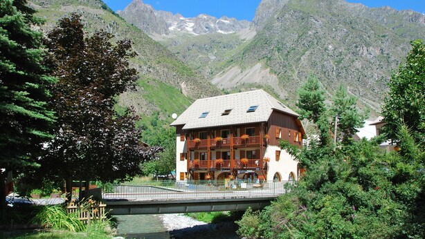 Un bâtiment de style chalet doté d’un balcon, d’un pont et surplombant un paysage montagneux.