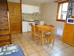 Una cocina compacta con una mesa y sillas de madera, un refrigerador blanco y un microondas sobre un mueble de madera.