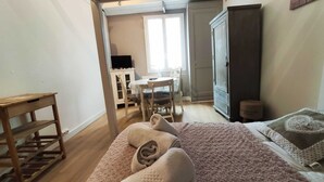 Een slaapkamer met een bed, een houten tafel, een kledingkast en een bureau met stoel.