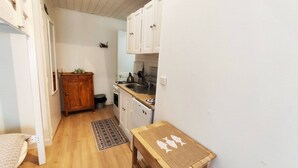 Een kleine keuken met houten kastjes, een klein aanrecht en een spoelbak.