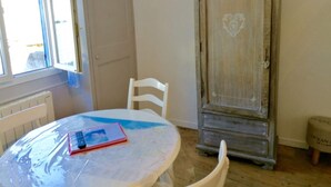 Een kamer met een ronde tafel, een witte stoel, een houten kastje met een hartmotief en een klein krukje.