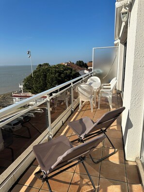 A balcony with two sun loungers, a glass door, and a view of the sea. - Luxury apartment with terrace, beach at the foot of the building (20 m) (Saint-Palais-Sur-Mer)