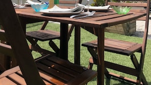 An outdoor dining area with a wooden table set for two, complete with wine glasses, a bottle of wine, and a menu. - New apartment, 4 people, ground floor, town center. (Cassis)