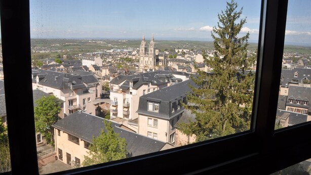 Blick aus einem Fenster auf eine Stadt mit einem markanten Kirchturm und Wohnhäusern.