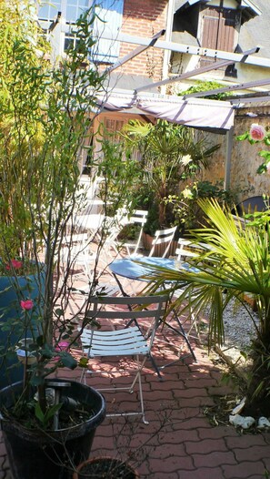 A patio area with a blue chair, white folding chairs, and potted plants. - Résidence Les Althéas - Apartment 3 (Villers-sur-Mer)