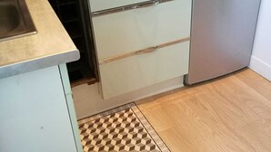 A kitchen with a gas stove, a stainless steel refrigerator, and a patterned rug. - Résidence Les Althéas - Apartment 3 (Villers-sur-Mer)