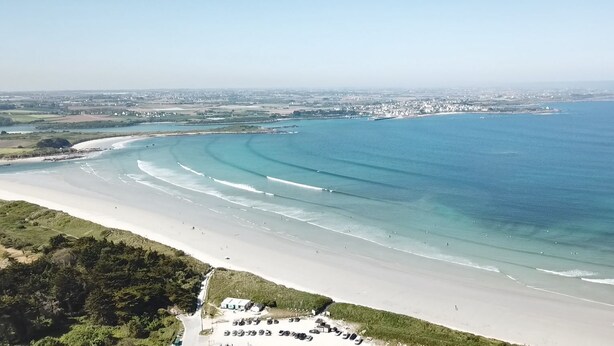 An aerial view of a coastal beach with a parking area and buildings in the distance. - CHARMING 4 **** in quiet, fully renovated, near the sea - PMR (Santec)