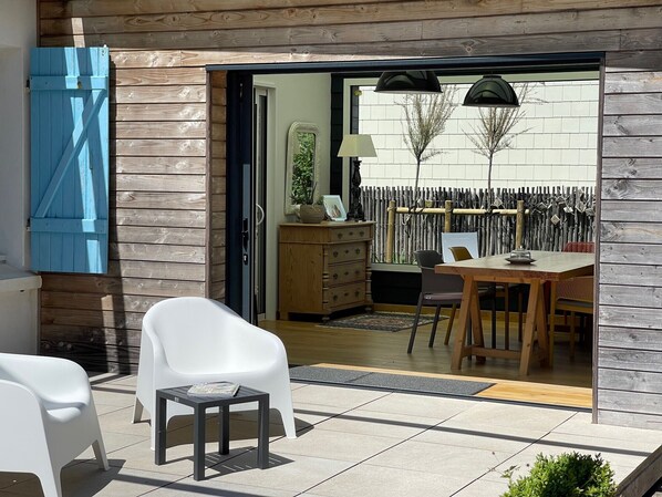 A patio with a dining table, chairs, and a small table with a magazine.