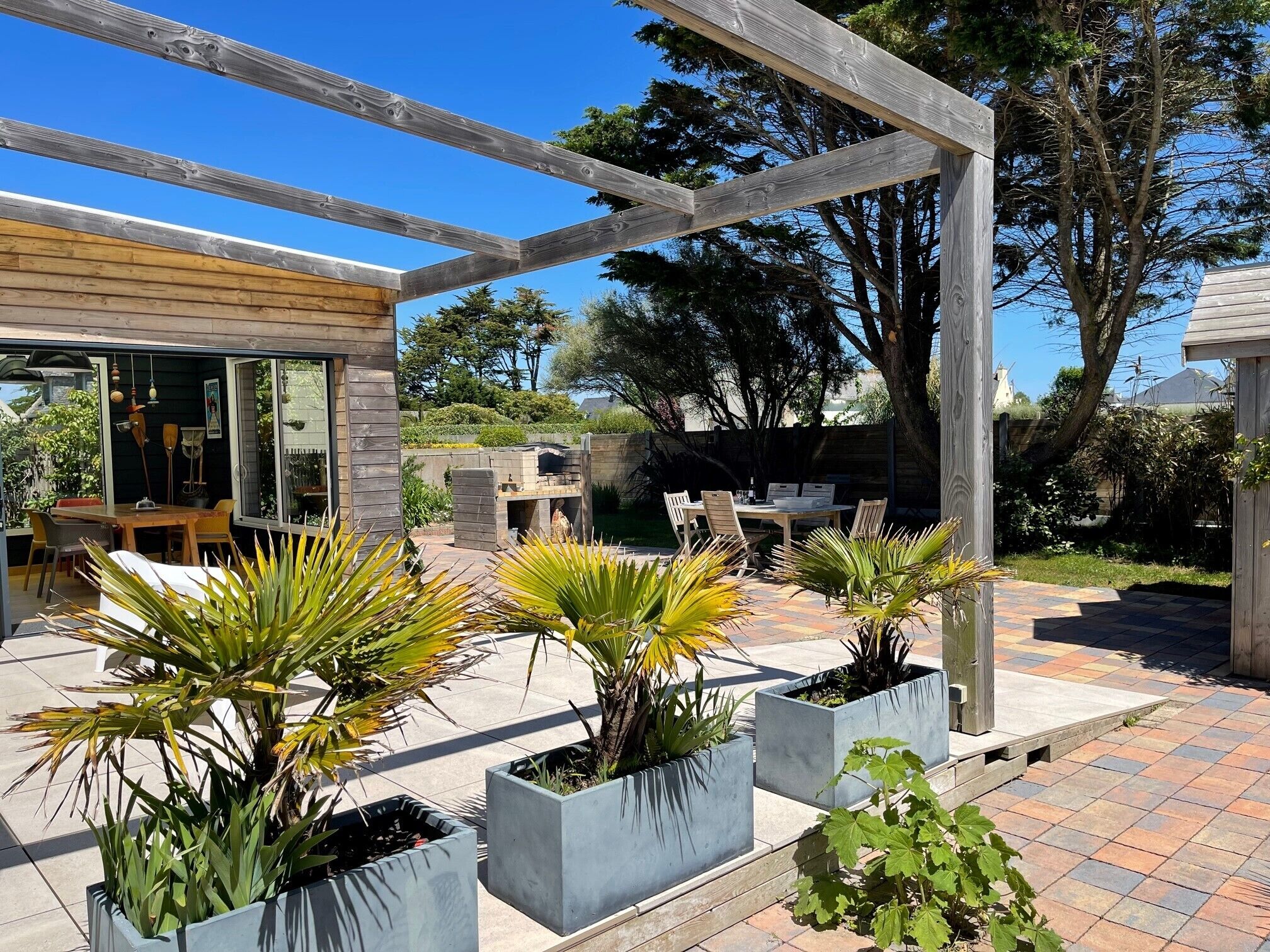Un espace patio agrémenté d’une pergola, de sièges d’extérieur et de plantes en pot.