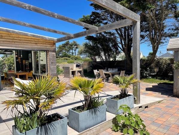 A patio area with a pergola, outdoor seating, and potted plants. - CHARMING 4 **** in quiet, fully renovated, near the sea - PMR (Santec)