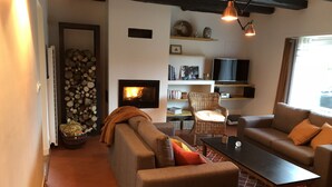 A cozy living room with a fireplace, sofas, a coffee table, and a television. - CHARMING 4 **** in quiet, fully renovated, near the sea - PMR (Santec)