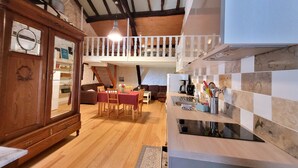 Eine gemütliche Küche mit Holzboden, eine Essecke mit Tisch und Stühlen sowie eine Treppe, die zu einer oberen Ebene führt.