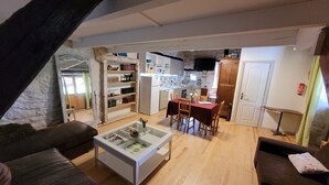 Ein gemütliches Wohnzimmer mit Kamin, ein Essbereich mit Tisch und Stühlen sowie eine Küche im Hintergrund.