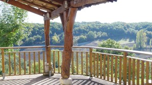 Eine Holzterrasse mit Geländer, die auf ein bewaldetes Tal blickt.