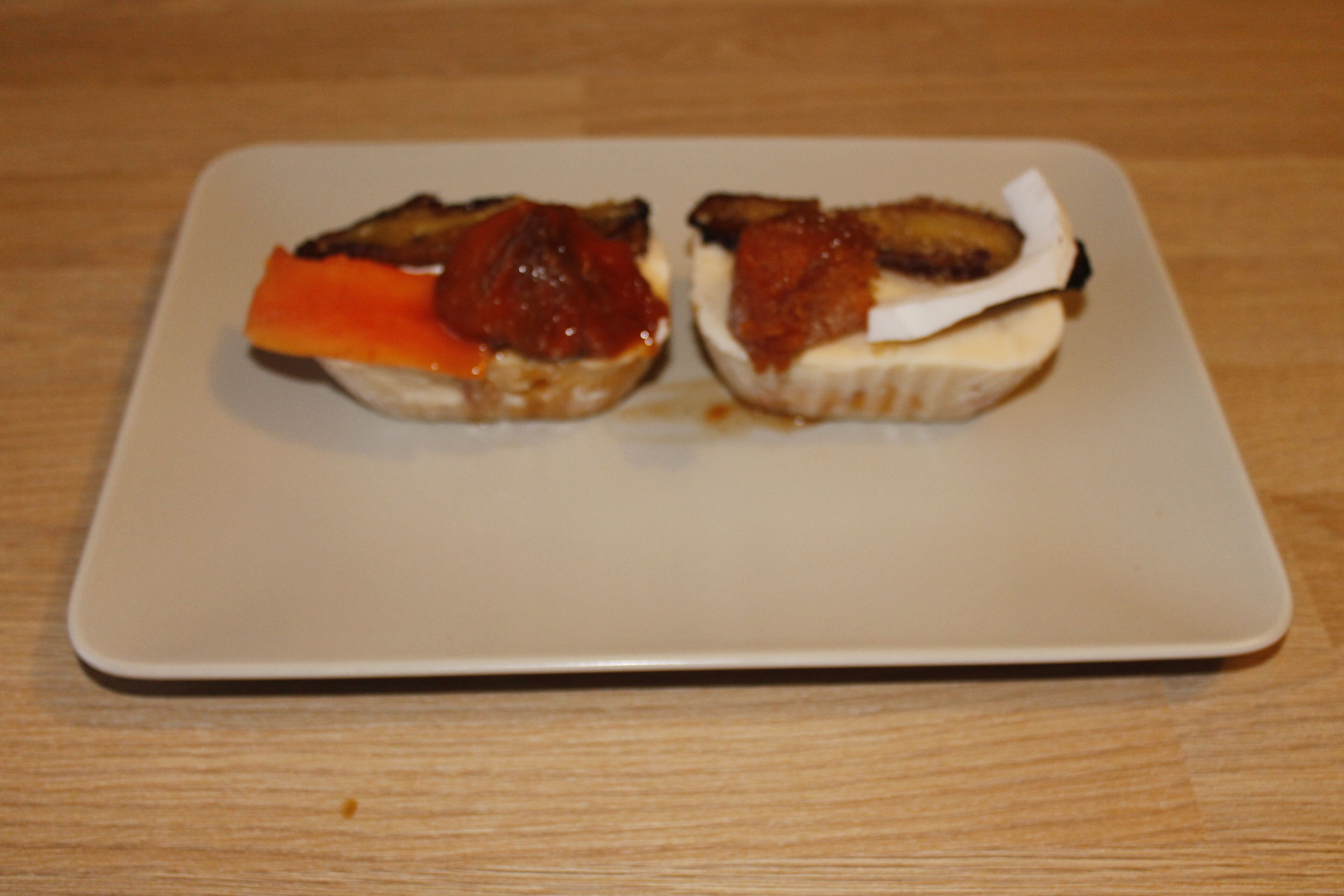 A square plate with two sandwiches on a wooden table.
