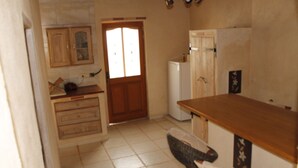 Une cuisine avec un plan de travail en bois, un réfrigérateur et une porte avec une fenêtre.