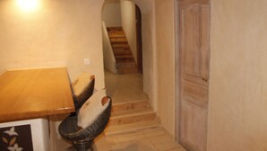 Un couloir étroit avec une table en bois et une chaise, une porte et un escalier menant à une autre pièce.