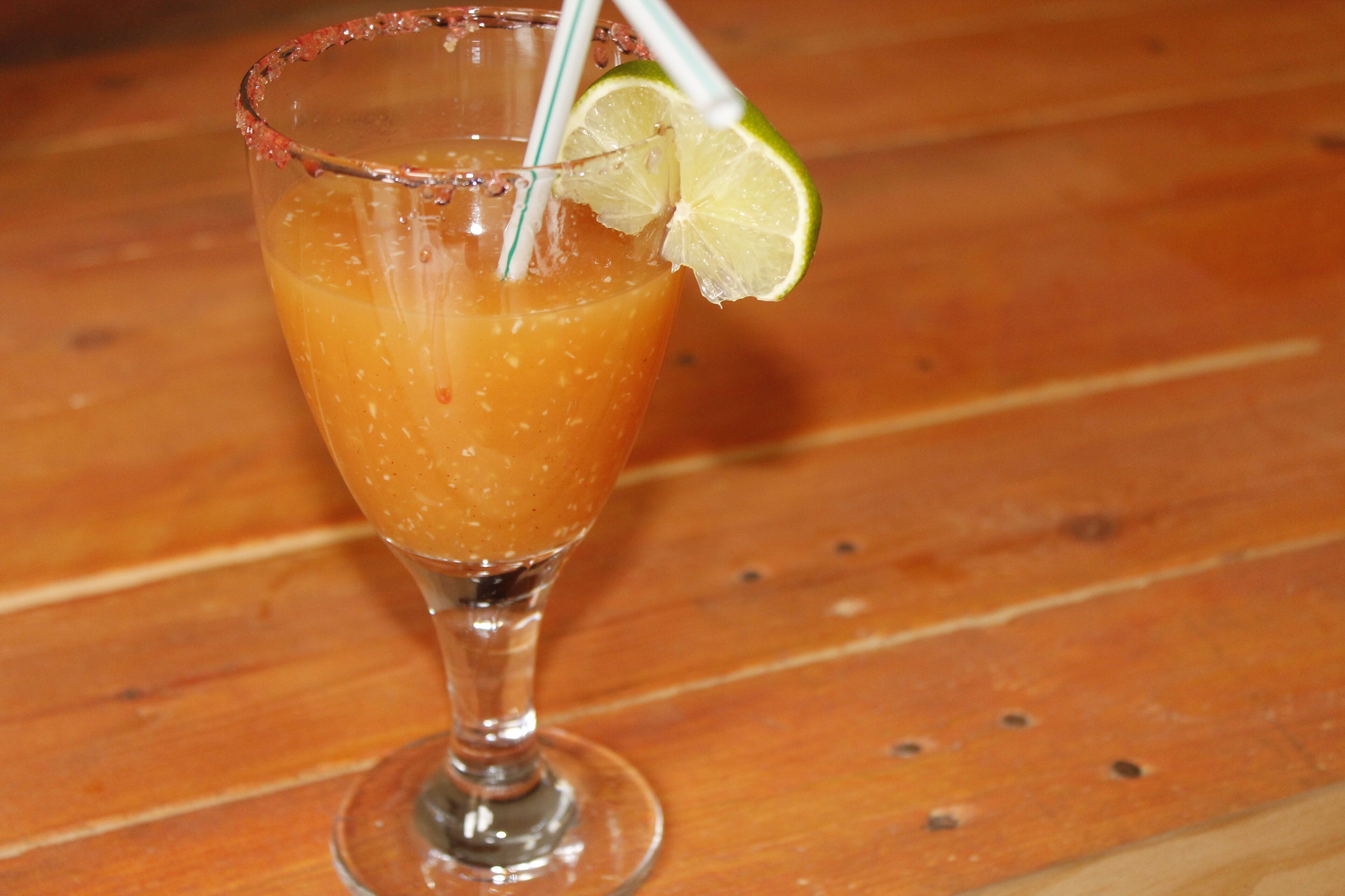 Un bicchiere da cocktail con una guarnizione di lime su un tavolo di legno.