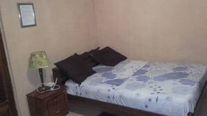 A bedroom with a bed, a nightstand, and a lamp. - Residence Oasis in Kinshasa (Kinshasa)