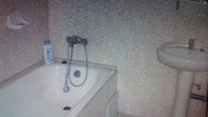 A bathroom with a bathtub, a sink, and a shower head. - Residence Oasis in Kinshasa (Kinshasa)