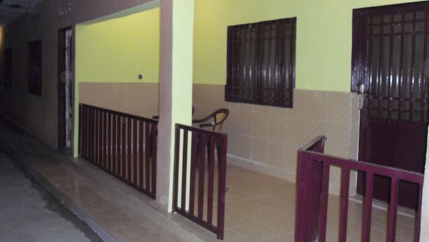 A covered outdoor area with a tiled floor, a wooden railing, and a bench. - Residence Oasis in Kinshasa (Kinshasa)