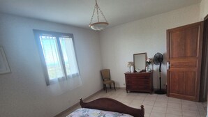 Une chambre à coucher avec un lit, une chaise, une commode, un miroir et une porte.