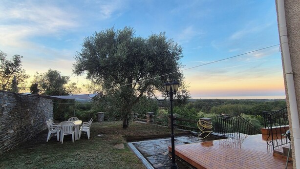 Une terrasse avec un mur en pierre, une table et des chaises, et une vue sur le paysage.