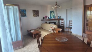 Un espace repas comprenant une table en bois, des chaises, un canapé, une cheminée et un luminaire suspendu au plafond.