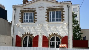 A building with a white facade, two windows with white frames, and red shutters. - Pretty Sablaise villa with garden close to beaches and shops (Les Sables-d'Olonne)