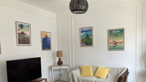 A living room with a TV, a coffee table, a sofa, and a patterned floor. - Pretty Sablaise villa with garden close to beaches and shops (Les Sables-d'Olonne)