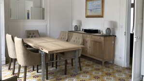 A dining area with a wooden table and chairs, a kitchen with a microwave and cabinets, and a painting on the wall. - Pretty Sablaise villa with garden close to beaches and shops (Les Sables-d'Olonne)