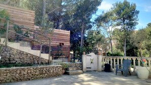 A stone wall, wooden fence, and a gate with a small garden area. - Large villa with pool in Provence near Les Baux de Provence, Nimes (Beaucaire)