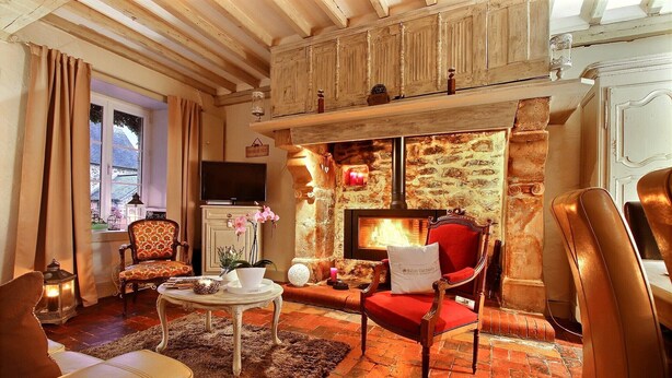 A cozy living room with a fireplace, wooden beams, a television, and comfortable seating.