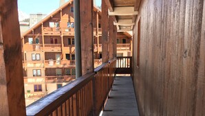 Een houten balkon met uitzicht op meerverdiepinggebouwen.