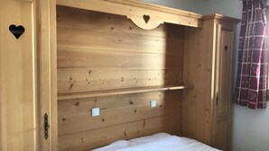 Een slaapkamer met een houten hoofdbord, een bed met witte beddengoed, en een deur met een hartvormig uitsparing.
