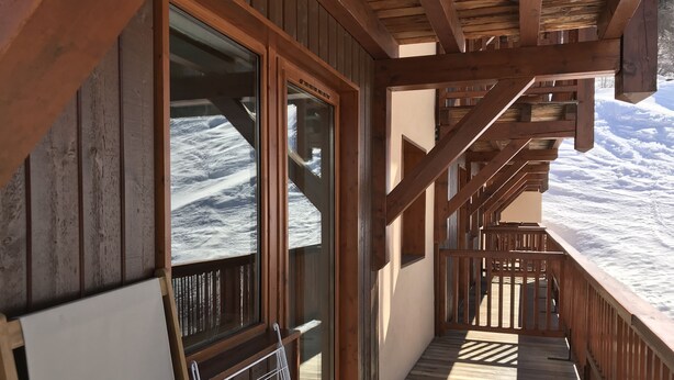 Een houten balkon met uitzicht op besneeuwde bergen.