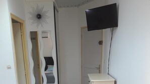 Ein Wohnzimmer mit einer Couch, einem an der Wand befestigten Fernseher und einem dekorativen Spiegel.