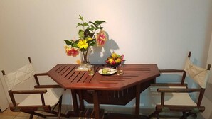 Ein Holzespeisetisch mit zwei Stühlen, einer Blumenvase und einem Teller mit Speisen und Getränken.